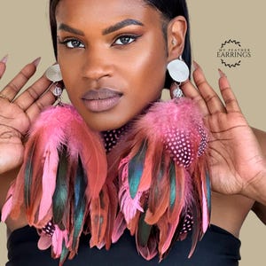 May include: Dangle earrings featuring silver-toned circular studs with a textured pattern, connected to long, layered feathers in shades of pink, brown, and iridescent green, with some feathers displaying white polka dots. Text reads MY FEATHER EARRINGS.