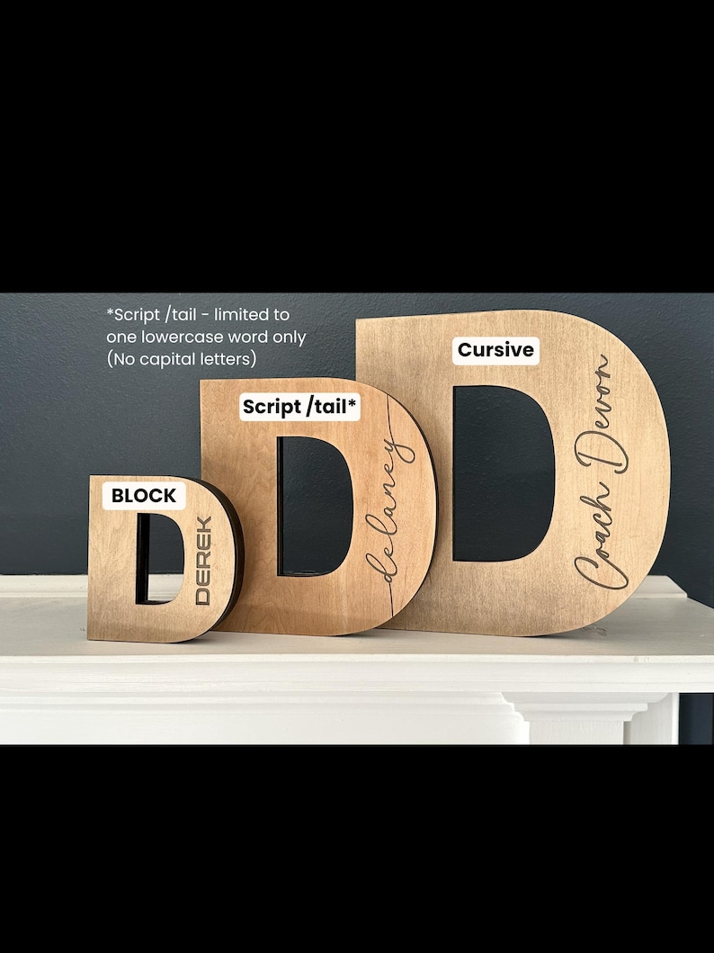 Pu&ograve; includere: Tre lettere in legno, ciascuna in uno stile diverso: blocco, scrittura e corsivo. Le lettere sono tutte la lettera "D" e sono personalizzate con nomi. La lettera in blocco dice "Derek", la lettera in scrittura dice "Delaney" e la lettera in corsivo dice "Coach Devon".