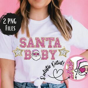 May include: A white t-shirt with the text "SANTA BABY" in pink glitter letters with gold glitter accents. A small image of Santa Claus wearing sunglasses is in the middle of the text. Two gold glitter stars are on either side of the text. The text "Realistic Detail!" is written in a pink heart shape.