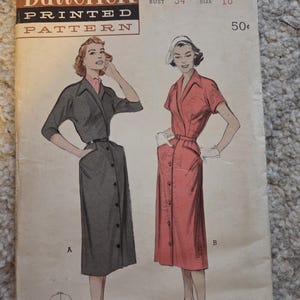 May include: Vintage Butterick printed sewing pattern showing illustrations of two button-down dresses. The pattern is labelled "6116" with a bust size of 34 and a size 16. The cover has a worn appearance.