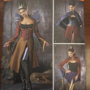 Puede incluir: Patrón de costura Simplicity 1138 para disfraces de fantasía. El patrón presenta ilustraciones de una mujer con varios diseños de disfraces, incluyendo una chaqueta de manga larga, una capa y una falda. Los disfraces tienen una temática medieval o élfica.