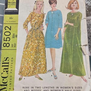 May include: Vintage McCall's printed pattern 8502. The pattern features illustrations of three robes in different colors and patterns: yellow floral, blue polka dot, and green. The bust size is 43 inches.