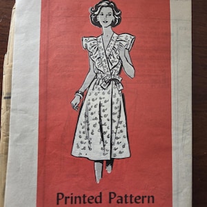 Puede incluir: Un patrón de costura impreso vintage con un diseño de vestido. La ilustración muestra a una mujer con un vestido cruzado con un estampado floral. El patrón está sobre un fondo rojo, con el texto "Printed Pattern" y "4815 - SIZE 12".