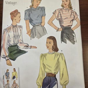May include: Vintage Simplicity sewing pattern 8736 for 1940s blouses. The pattern features illustrations of four different blouse styles, including a striped short-sleeve top and a long-sleeve blouse. The pattern size is U.S. 6-14.