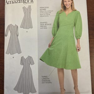 Może przedstawiać: Wzór szycia Simplicity S8831 AA Amazing Fit. Wzór przedstawia zieloną sukienkę z dekoltem w kształcie litery V i długimi rękawami. Wzór zawiera szwy księżniczki, ukształtowane elementy boczne i trzy opcje długości. Rozmiar U.S. 10-18, Euro 36-44.