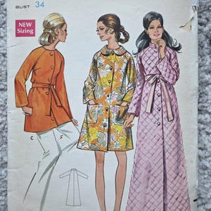 May include: Vintage Butterick sewing pattern 5556. The pattern features illustrations of three different coat designs. The cover shows a woman in an orange coat, a floral coat, and a pink quilted robe. The size is 12, with a bust measurement of 34 inches.