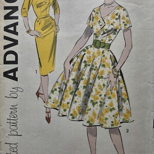 May include: Vintage sewing pattern by Advance featuring two dress designs. One is a yellow wrap dress, and the other is a white dress with a yellow floral print, a green belt, and a flared skirt. The pattern size is 14.