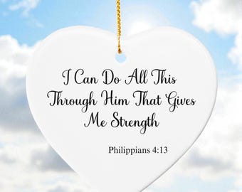 May include: White heart-shaped ornament with gold chain, against a blue sky. The ornament has the text "I Can Do All This Through Him That Gives Me Strength" and "Philippians 4:13" in black script.