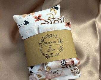 Puede incluir: Un conjunto de pequeños artículos de tela rectangulares con estampados florales en tonos blancos, marrones y melocotón, sujetos por una banda de papel marrón. La banda presenta el texto "Handmade by Wonnie" dentro de una corona decorativa.