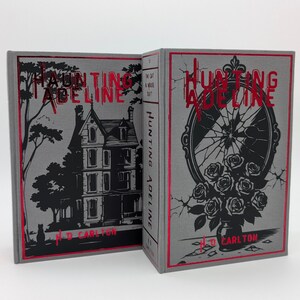 May include: Two hardcover books titled "Hunting Adeline" by H.D. Carlton. The books have gray covers with red accents. One cover features a house illustration, the other a broken mirror with roses. The spine reads "Hunting Adeline".