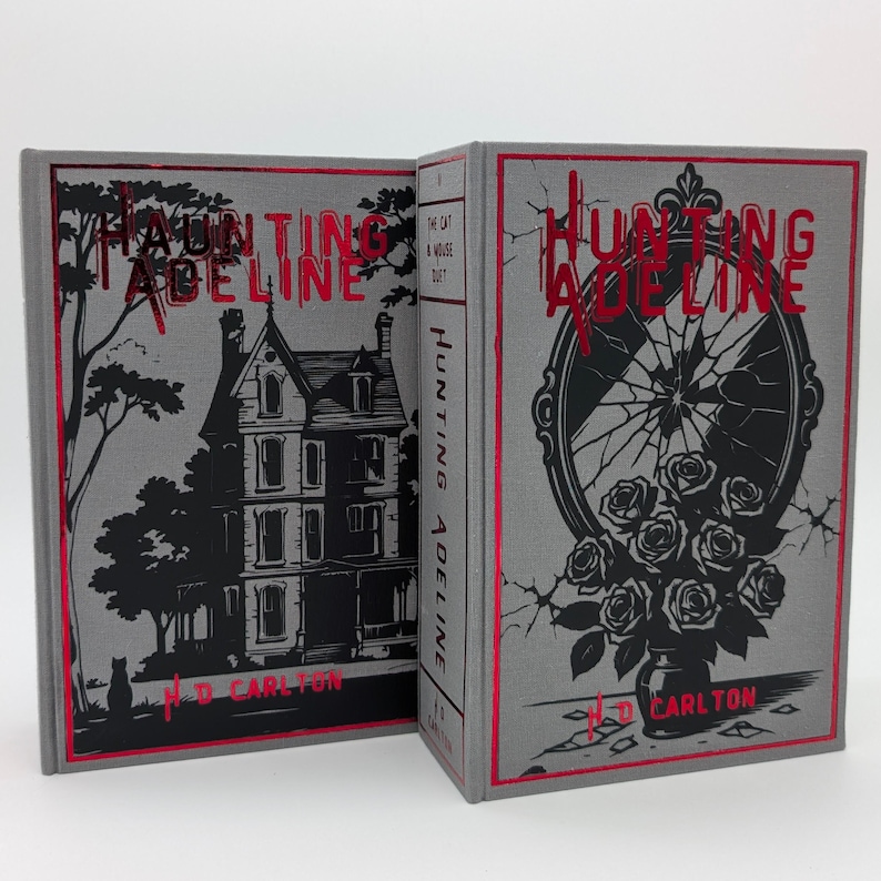 May include: Two hardcover books titled "Hunting Adeline" by H.D. Carlton. The books have gray covers with red accents. One cover features a house illustration, the other a broken mirror with roses. The spine reads "Hunting Adeline".