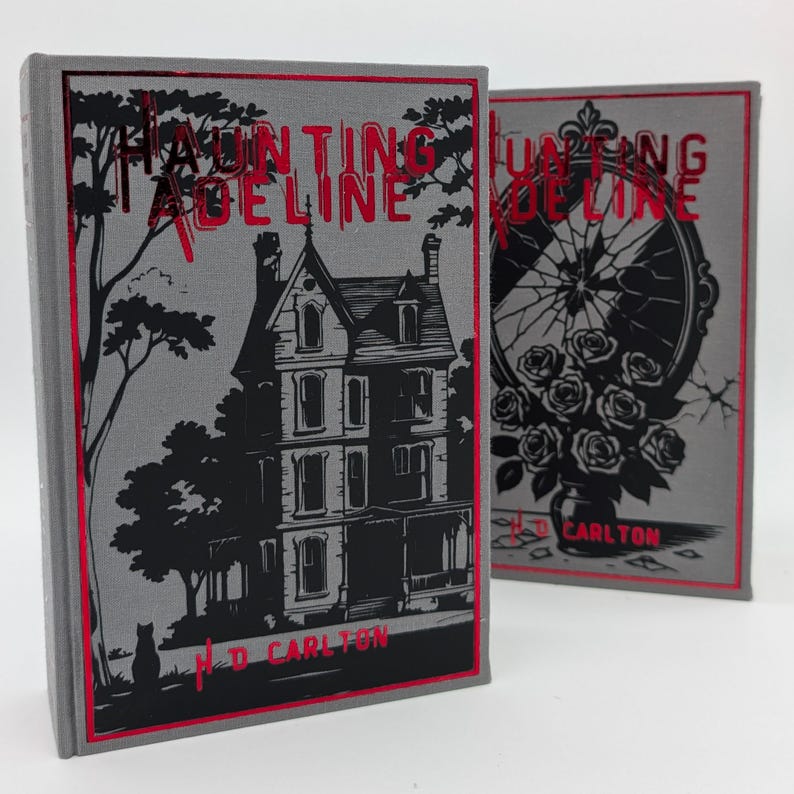 May include: Two hardcover books with gray covers and red borders. The title "Haunting Adeline" is in red, with a black illustration of a house and a cat on one book. The author's name, H.D. Carlton, is at the bottom.