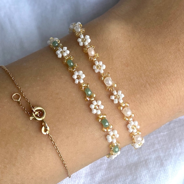 Zartes elegantes Perlenarmband in Pastellfarben mit kleinen goldenen Details und weißen Gänseblümchen-Blüten