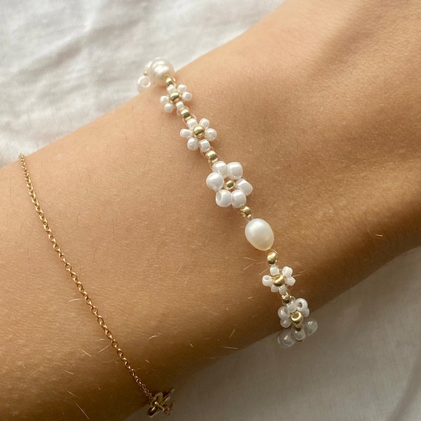 Bracelet fleurs blanches de différentes tailles avec perles d'eau douce et détails dorés
