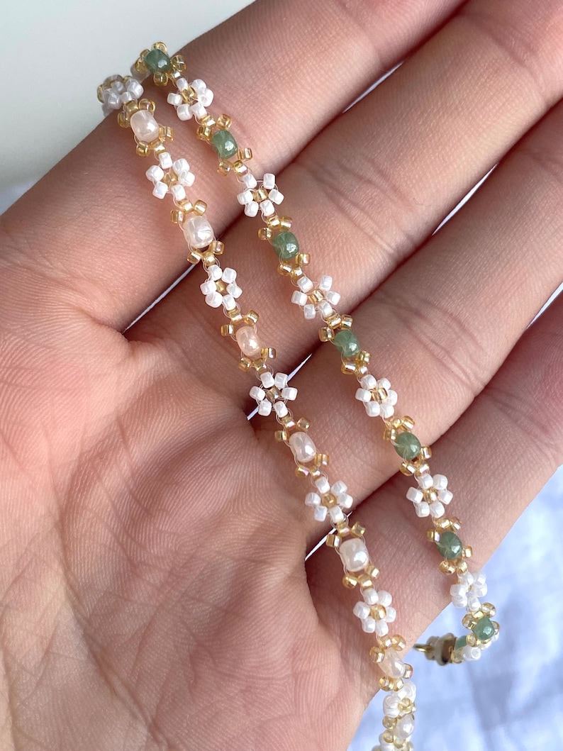 Zartes elegantes Perlenarmband in Pastellfarben mit kleinen goldenen Details en witte Gänseblümchen-Blüten afbeelding 9