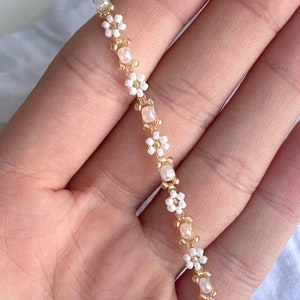 Zartes elegantes Perlenarmband in Pastellfarben mit kleinen goldenen Details en witte Gänseblümchen-Blüten afbeelding 7