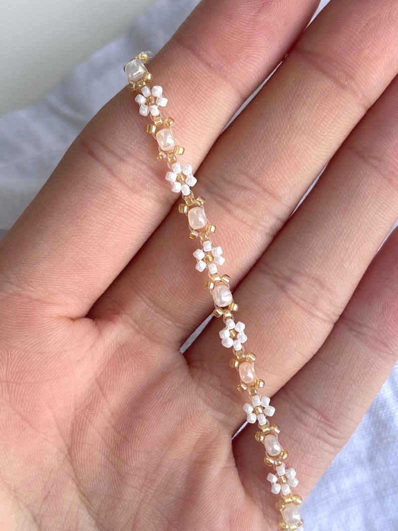 Zartes elegantes Perlenarmband in Pastellfarben mit kleinen goldenen Details e weißen Gänseblümchen-Blüten immagine 7