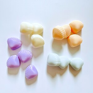 May include: Assortment of colourful shell-shaped wax melts in purple, light blue, cream, and peach.