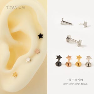 Könnte beinhalten: Sternförmige Ohrringe aus Titan in Schwarz, Roségold, Gold und Silber. Das Bild zeigt die Ohrringe in verschiedenen Ausführungen, darunter Labret-Ohrstecker. Der Text auf dem Bild lautet "TITANIUM" und "16g / 18g / 20g".