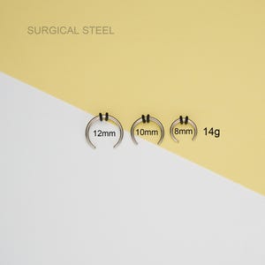 May include: Three surgical steel nose rings in different sizes: 8mm, 10mm, and 12mm. The rings are 14 gauge and have black rubber o-rings.