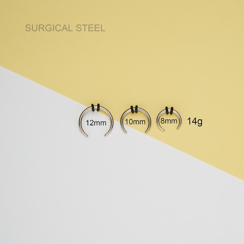 May include: Three surgical steel nose rings in different sizes: 8mm, 10mm, and 12mm. The rings are 14 gauge and have black rubber o-rings.