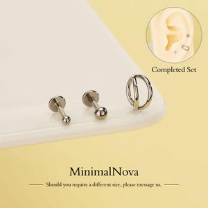 Puede incluir: Un conjunto de pendientes plateados, que incluye dos tachuelas de espalda plana con extremos de bola y un pendiente de doble aro. Un diagrama muestra los pendientes en una oreja. El texto "Completed Set" es visible. También se muestra el nombre de la marca "MinimalNova".