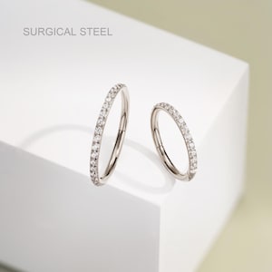 May include: Two surgical steel seamless rings with a row of clear cubic zirconia stones around the edge.