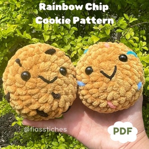 Könnte beinhalten: Zwei gehäkelte Plüsch-Kekse, einer mit Schokoladenstückchen und einer mit Regenbogenstreuseln. Die Kekse haben lächelnde Gesichter und werden in einer Hand gehalten. Der Text "Chocolate Chip & Rainbow Chip Cookie Pattern" und "PDF" ist auf dem Bild zu sehen.
