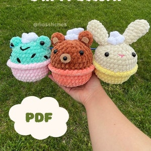 Op de afbeelding: Drie gehaakte ijshoorntjesvrienden, een kikker, een beer en een konijn, met een roze, oranje en gele hoorntje, respectievelijk. De afbeelding bevat de tekst "Ice Cream Pals 3 in 1 Pattern" en "PDF".