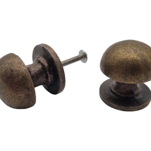 May include: Two antique brass cabinet knobs with a round, domed top and a flat base. The knobs have a textured finish and come with screws.