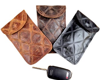 May include: Three leather phone cases with a quilted diamond pattern. The cases are brown, black, and dark brown. A black car key with the Audi logo is in the foreground.