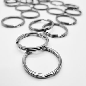 May include: A close-up of a pile of silver key rings. The key rings are all the same size and shape, and they are arranged in a random pattern.