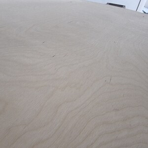 May include: A close-up of a light brown wood surface with a smooth, even texture. The surface has a subtle grain pattern.