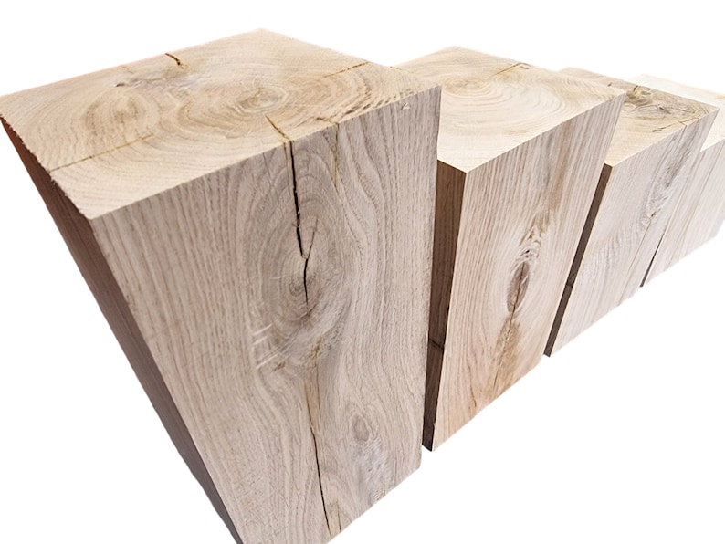 May include: Four wooden blocks stacked in a staggered formation, showcasing the natural grain and knots of the wood. The blocks are light brown in color and have a rough, unfinished texture.