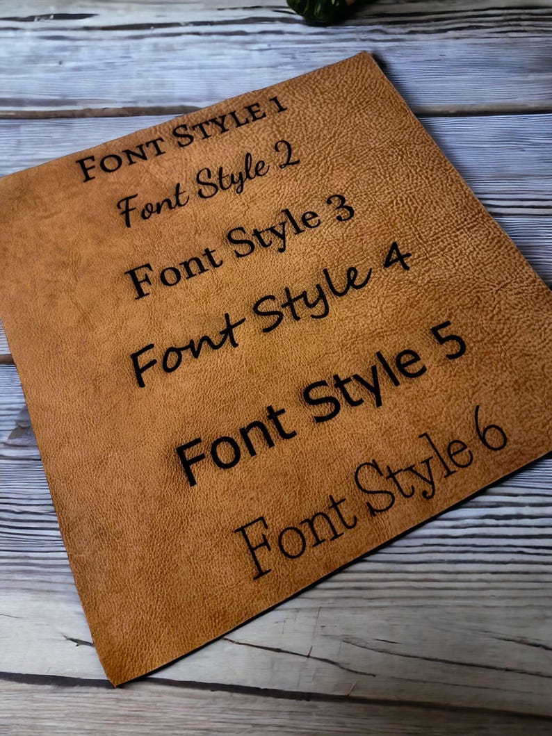 K&ouml;nnte beinhalten: Nahaufnahme einer braunen Lederoberfl&auml;che mit sechs verschiedenen Schriftarten in Schwarz gedruckt. Der Text lautet "FONT STYLE 1", "Font Style 2", "Font Style 3", "Font Style 4", "Font Style 5" und "Font Style 6".