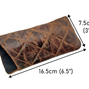 May include: Brown leather glasses case with a quilted pattern. The case measures 16.5 cm long and 7.5 cm wide.