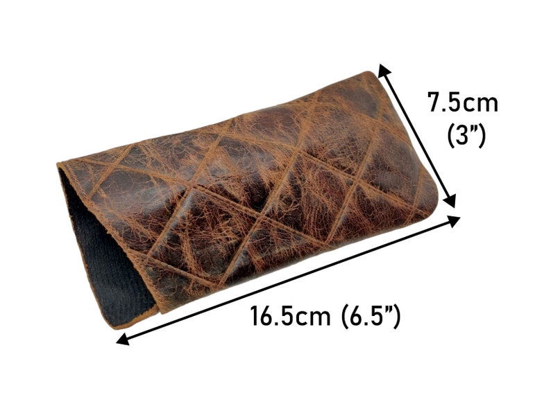 May include: Brown leather glasses case with a quilted pattern. The case measures 16.5 cm long and 7.5 cm wide.