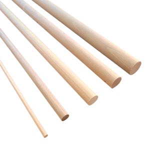 May include: A selection of unfinished wooden dowels in different sizes. The dowels are a light brown hue, displaying a smooth, natural wood grain. The ends are rounded, and the dowels are positioned diagonally across the image.