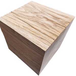 May include: A natural wood cube stool with a light brown finish and visible wood grain.