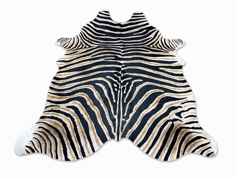 Pode incluir: Um tapete com estampa de zebra com uma forma &uacute;nica. O tapete apresenta listras pretas e bege, com detalhes brancos nas bordas. O tapete foi projetado para se assemelhar a uma pele de zebra e est&aacute; sobre um fundo branco.