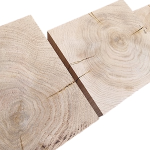 May include: Three pieces of light brown wood with visible grain patterns and knots. The wood is arranged horizontally, with the grain patterns running in different directions.