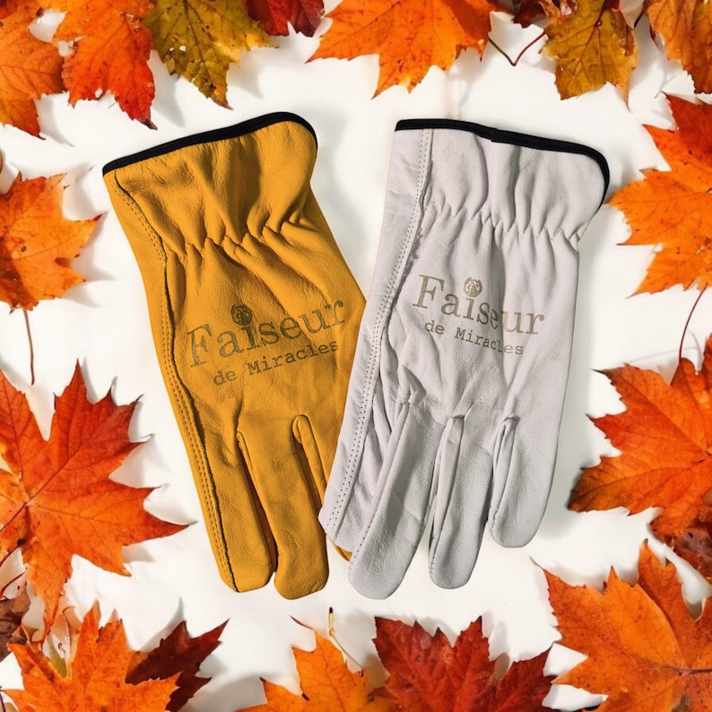 May include: Two pairs of leather work gloves, one tan and one white, with the text "Faiseur de Miracles" embroidered on each glove.