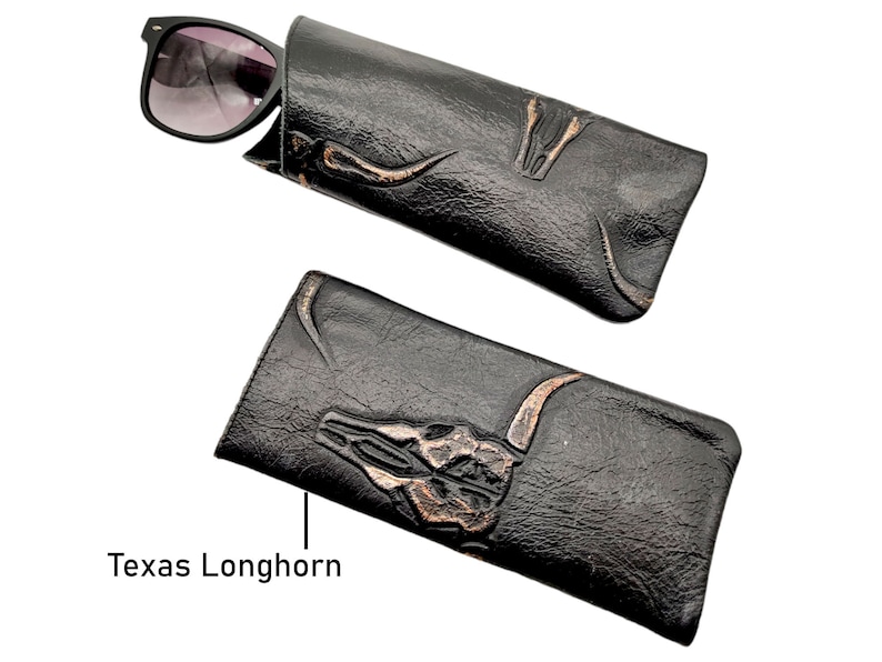 May include: Black leather glasses case with a tooled design of a Texas Longhorn skull. The case is closed with a pair of sunglasses inside.