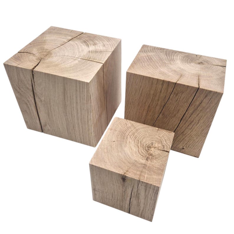 May include: Three wooden cubes of varying sizes, each with a natural wood grain and a rough, unfinished texture. The cubes are stacked on top of each other, with the largest cube at the bottom and the smallest cube at the top.