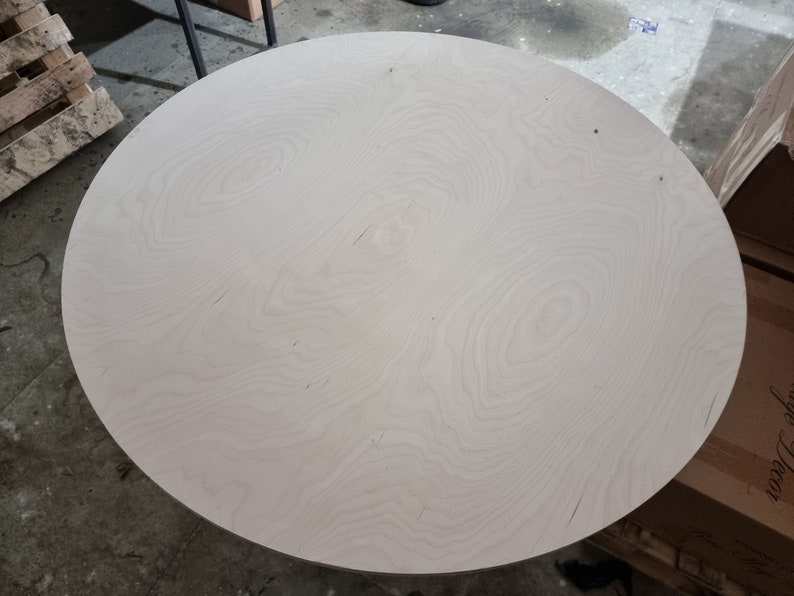 May include: A round, white, wooden tabletop with a natural wood grain pattern.