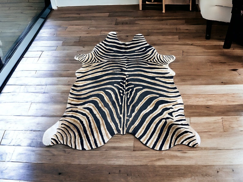 Pode incluir: Um tapete com estampa de zebra com listras pretas e bege. O tapete tem formato de pele de animal e est&aacute; colocado em um piso de madeira. O design do tapete imita o padr&atilde;o da pelagem de uma zebra, adicionando um toque selvagem ao ambiente.