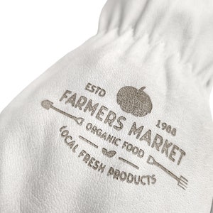 May include: White leather bag with a brown logo that says "Estd Farmers Market 1968 Organic Food Local Fresh Products". The logo also includes a tomato, a shovel, and a fork.