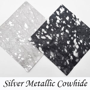 May include: Two pieces of cowhide fabric, one silver metallic with white spots and one black with white spots.
