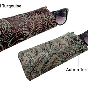 May include: Two turquoise leather sunglasses cases with an embossed floral pattern. The case on the left is labelled "Floral Turquoise" and the case on the right is labelled "Autumn Turquoise".