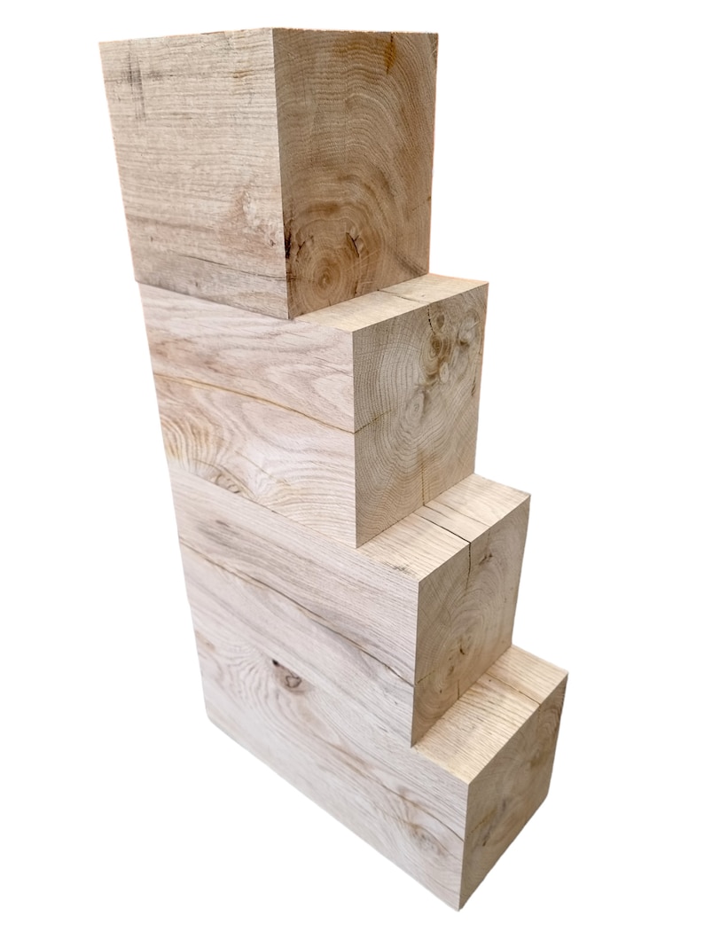 May include: Four wooden blocks stacked on top of each other, each block is slightly smaller than the one below it. The blocks are made of light-colored wood with a natural grain pattern.